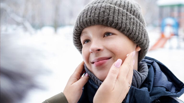 Mother applies cream to child's face
