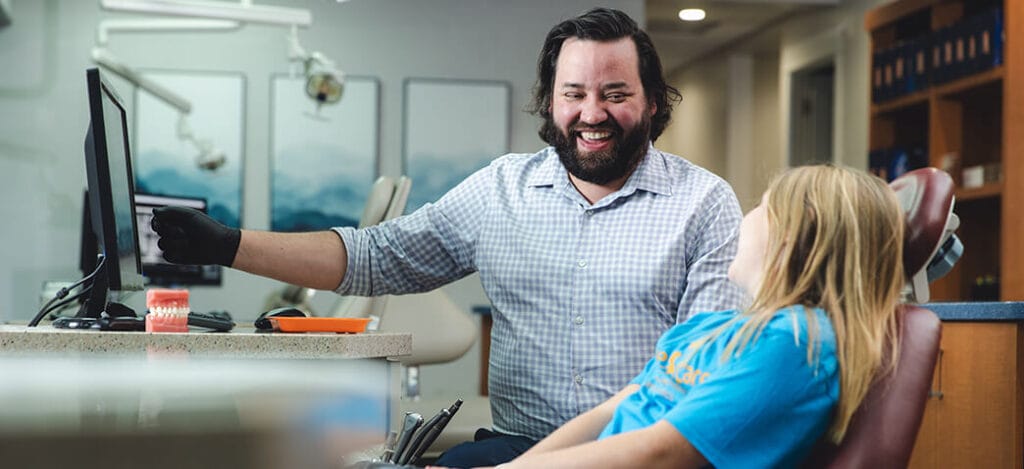Layton orthodontist, Casey Brewer, smiles with a young patient in the exam room