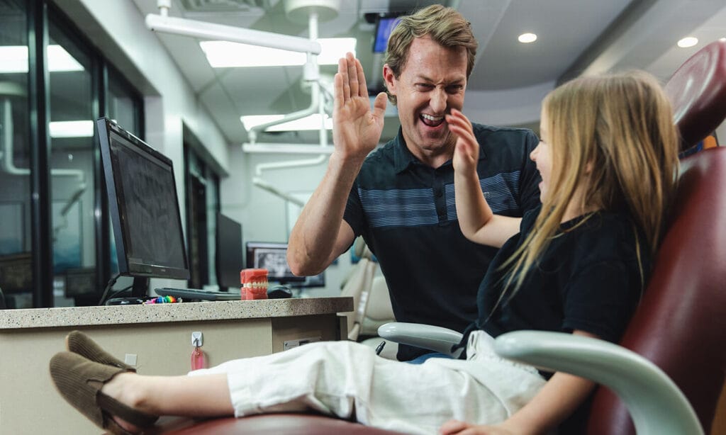 Chris Neeley, DDS high fives a smiling young patient