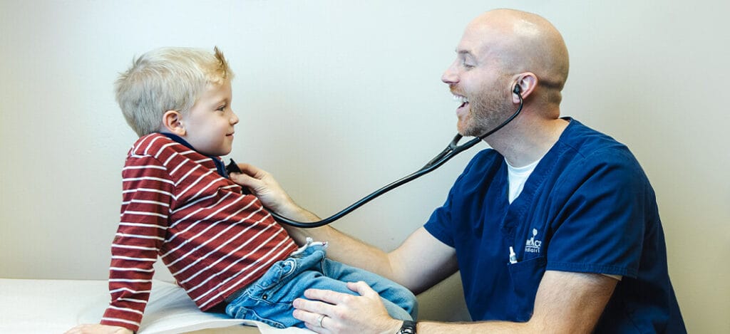 Provider portrait Colton Ragsdale, M.D. smiling with a young patient during an exam