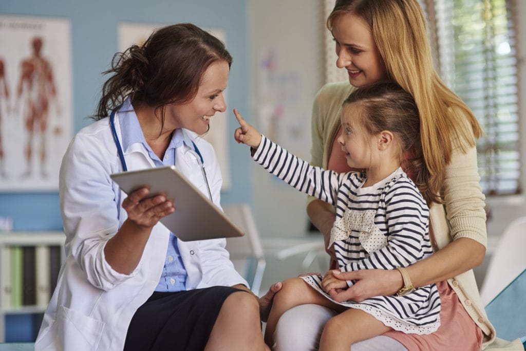 A child smiles at her pediatrician in a clinic setting