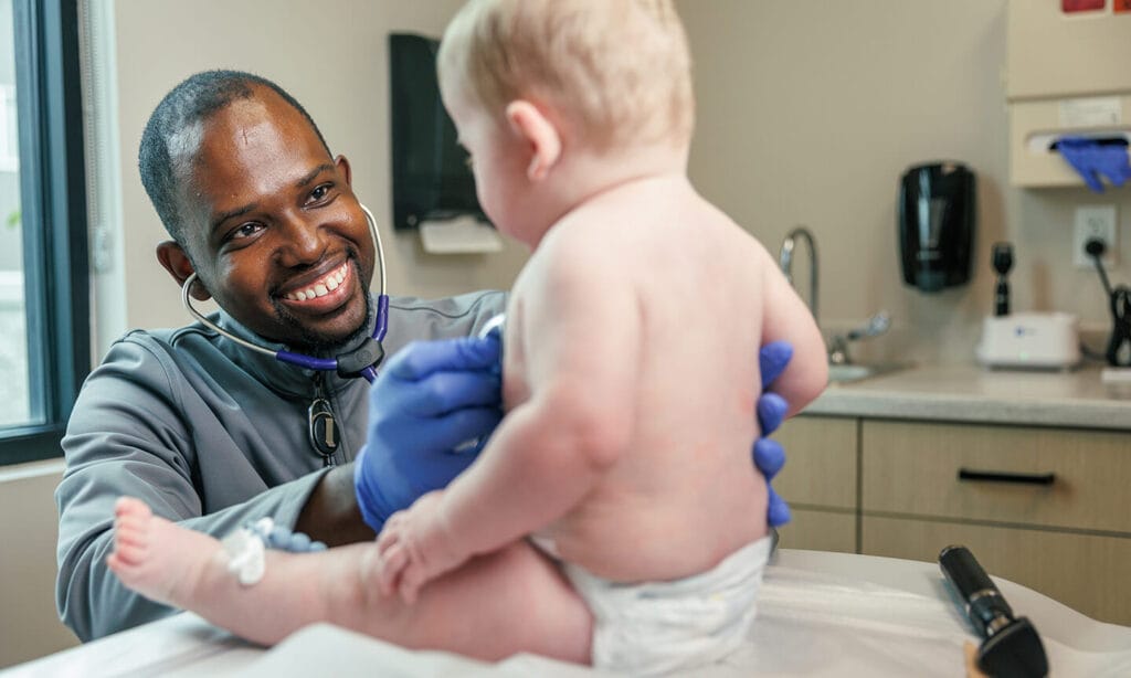 Perry J. Leonard Jr., MD, MSPH, MHS interacts with an infant patient.