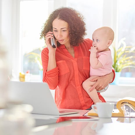 Mother views a laptop while holding an infant