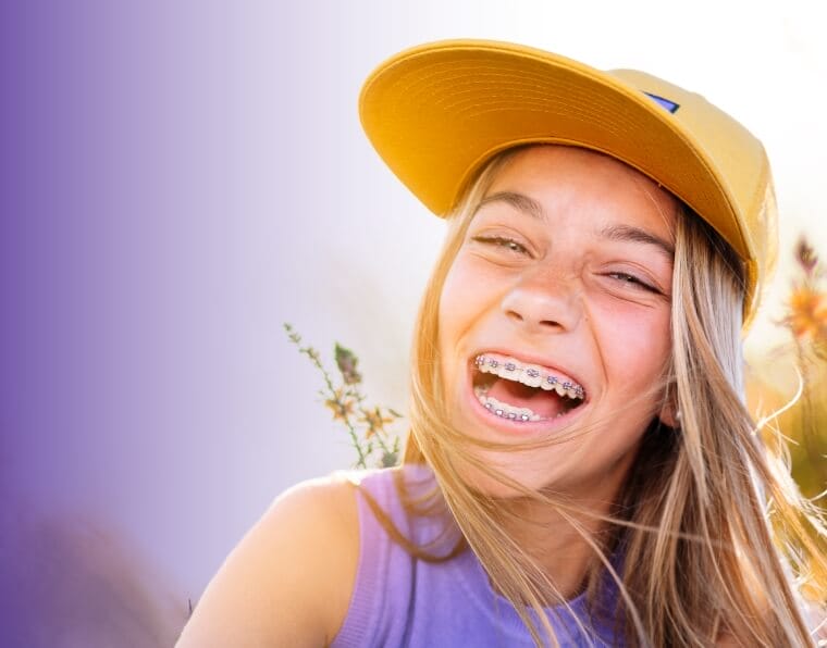 young girl smiling with braces on in a field of wildflowers