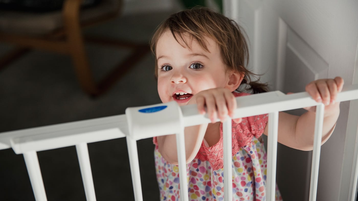 Young toddler trying to look over baby gate
