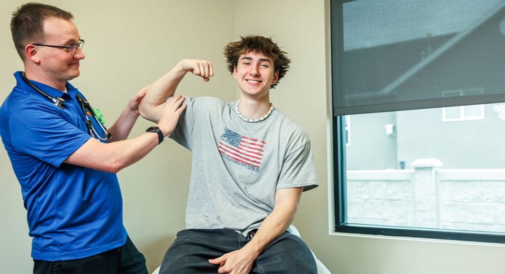 Teen flexing his muscles with his pediatrician