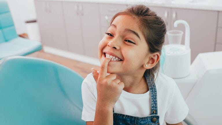 young girl at the dentist smiling and showing her teeth