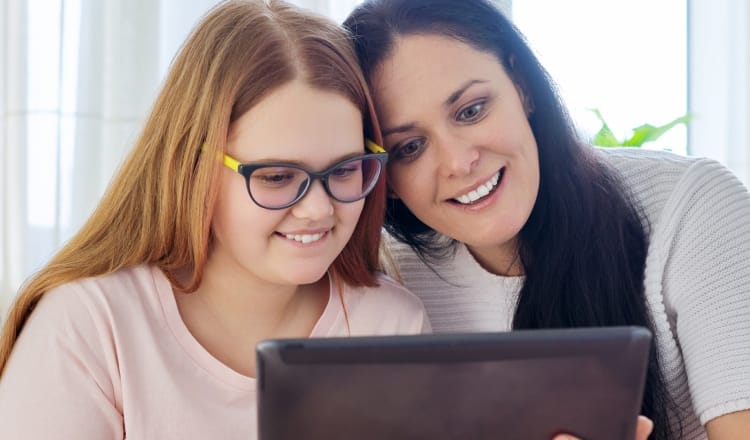 Smiling mother and daughter use a tablet
