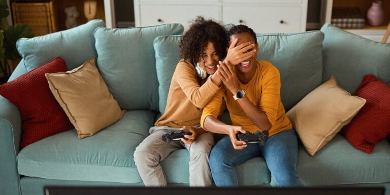 Smiling son and mother playing video games on the couch