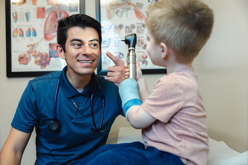 Smiling pediatrician interacts with his young patient