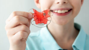 Young boy holding up retainer
