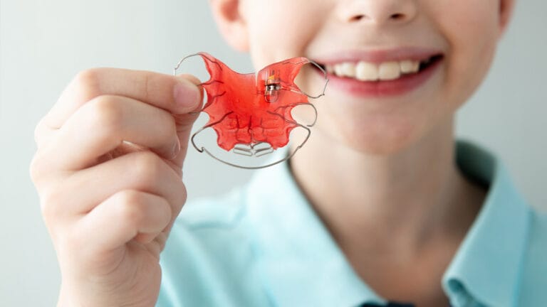 Young boy holding up retainer