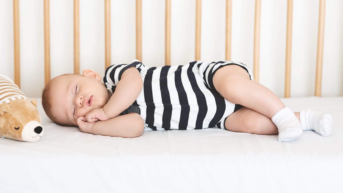 newborn baby boy sleeping on his side in a crib