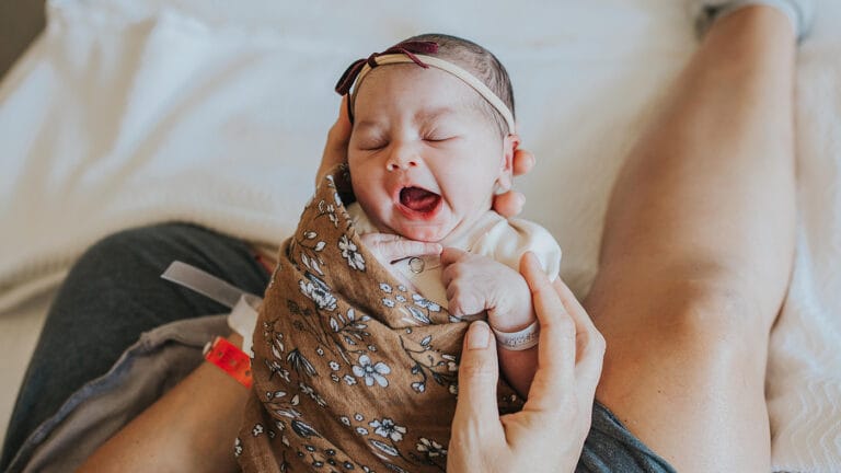 new mom holding newborn baby girl in the hospital