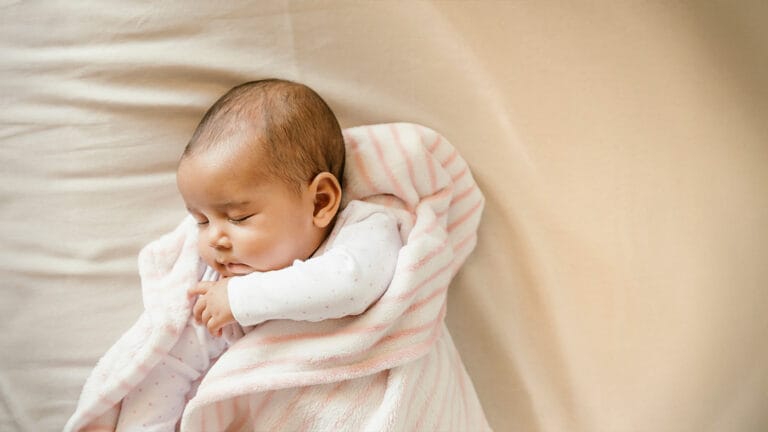 Young newborn sleeping in baby blanket