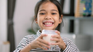 Little girl with a glass of milk smiling with a milk mustache