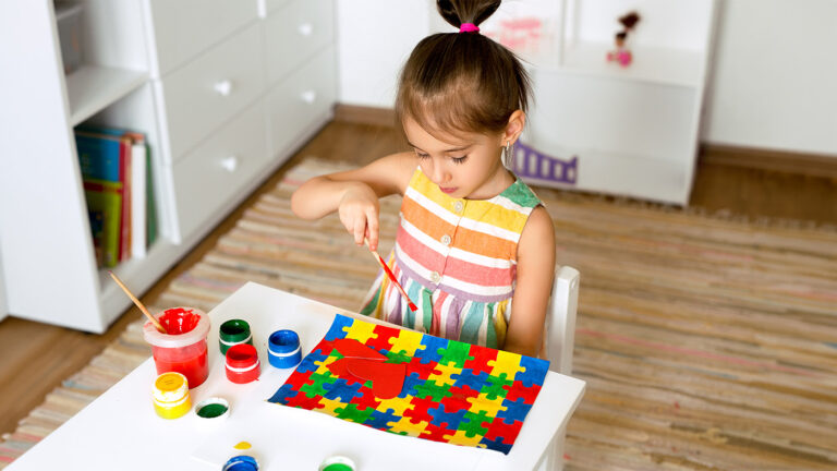 Young girl using paints to paint a colorful puzzle