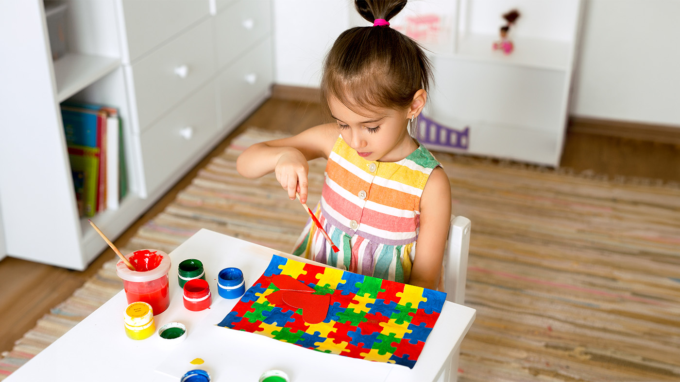 Young girl using paints to paint a colorful puzzle
