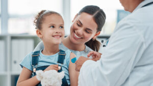 Mother with daughter in her lap while she gets a vaccination shot.
