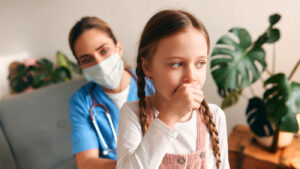 Pediatrician observing young girl coughing