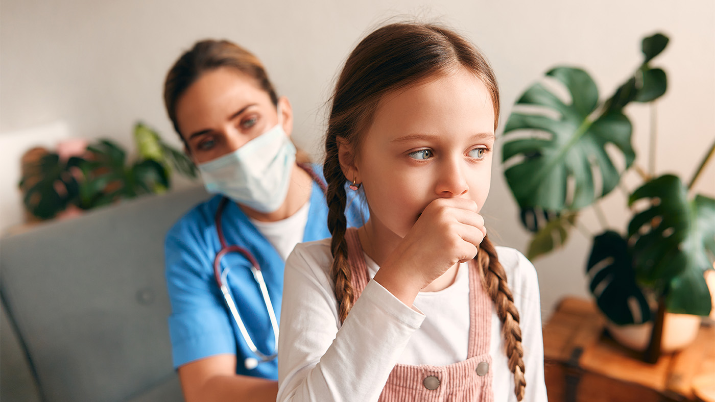 Pediatrician observing young girl coughing