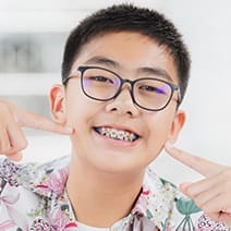 Teen smiles and points at their braces