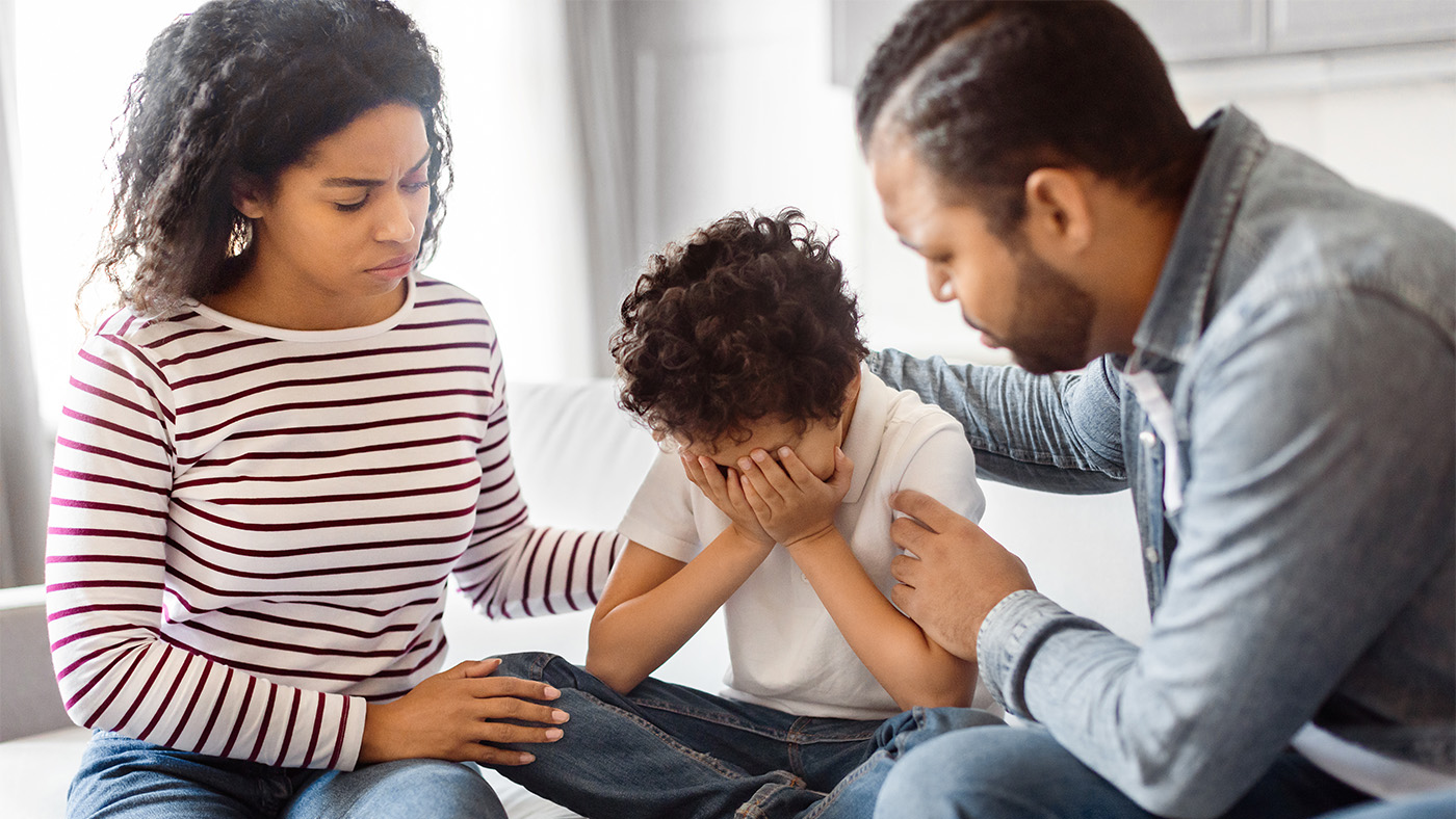Young parents consoling their crying chlid on the couch