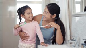 mom and young daughter brushing their teeth