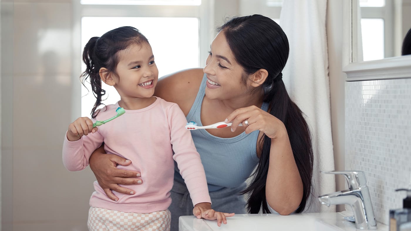 mom and young daughter brushing their teeth