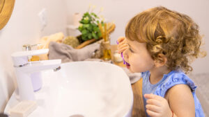 young toddler brushing her teeth in the mirror