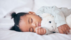 Young child sleeping with a stuffed animal