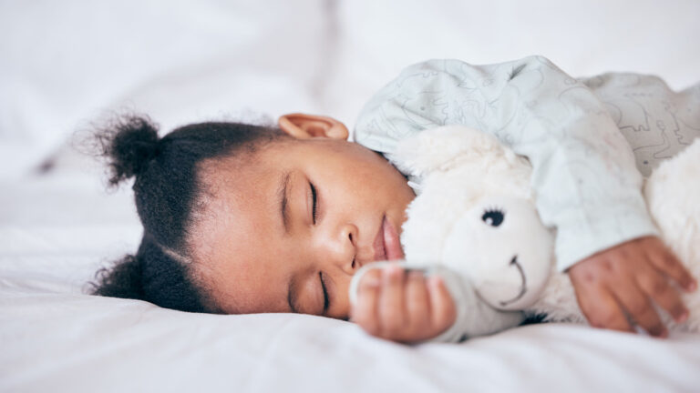 Young child sleeping with a stuffed animal