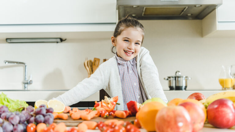 Young girl in kitchen surrounded by fruits and vegetables