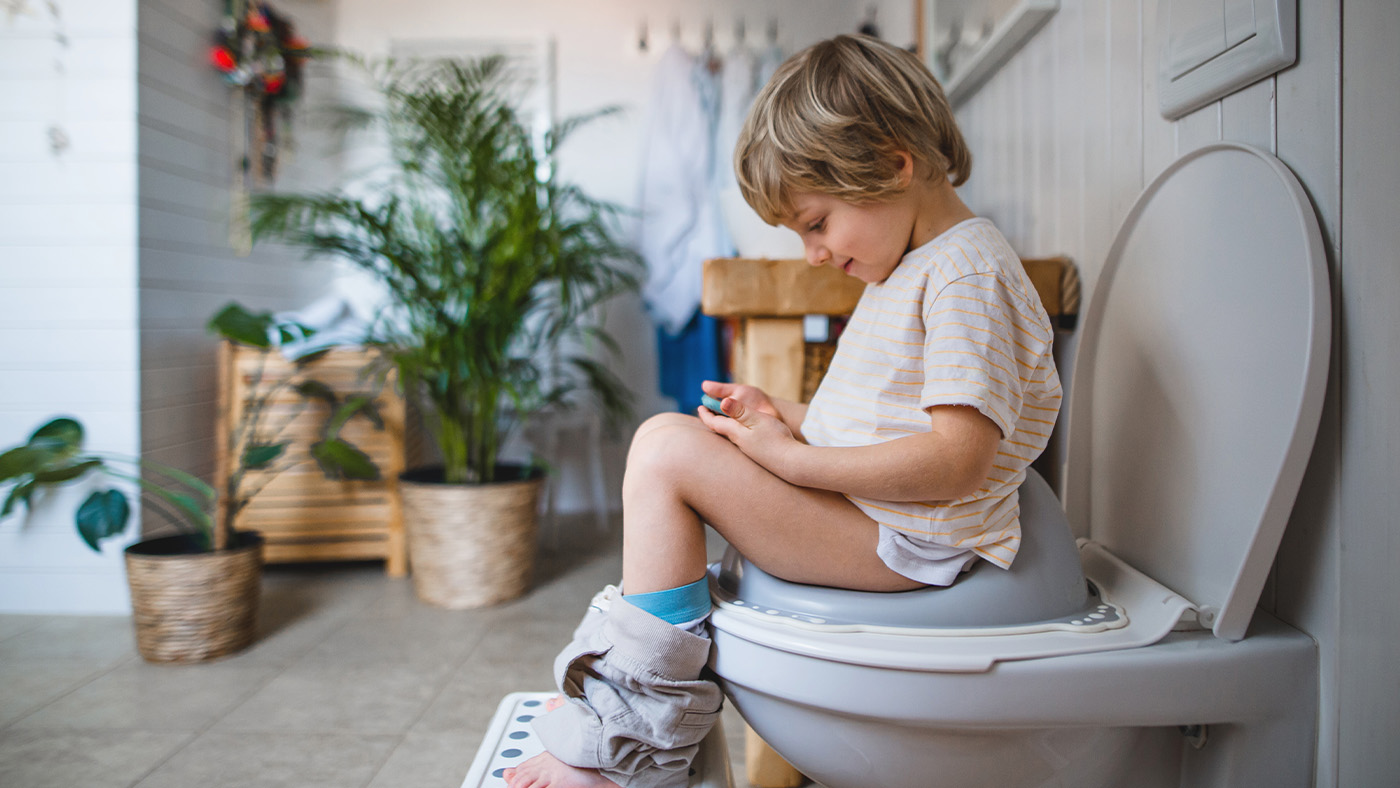 Young boy on potty with phone